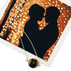 A custom photo necklace featuring an image of a couple in silhouette at their wedding